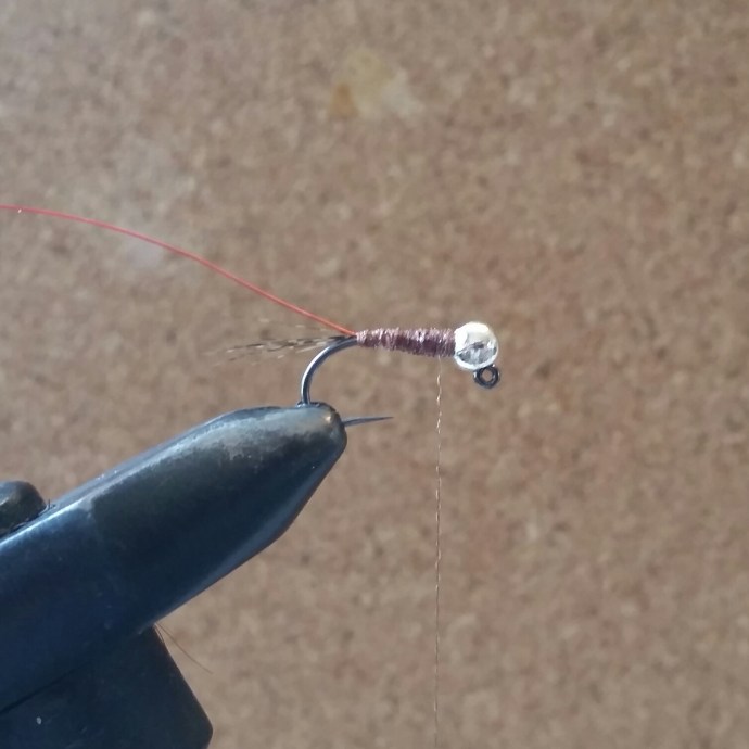 Now I switch bobbins to the Nymph-It and create the body in touching turns towards the bend. I don't mind gaps here but the more anal fly tier may want to take their time here. On the way back up the shank I use the Nymph-It to create a rib for the wire to follow. Tie off with Nymph-It with a couple of whip finishes - apply some varnish again if you like.