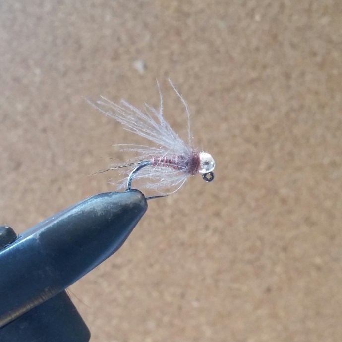 Apply a healthy amount of ice dub to your thread and dub over the gap between the hackle and the bead. Whip finish tightly so that the therad cinches down below the dubbing. Varnish if you wish. There it is, the Dzigi Dzigi in all its glory!